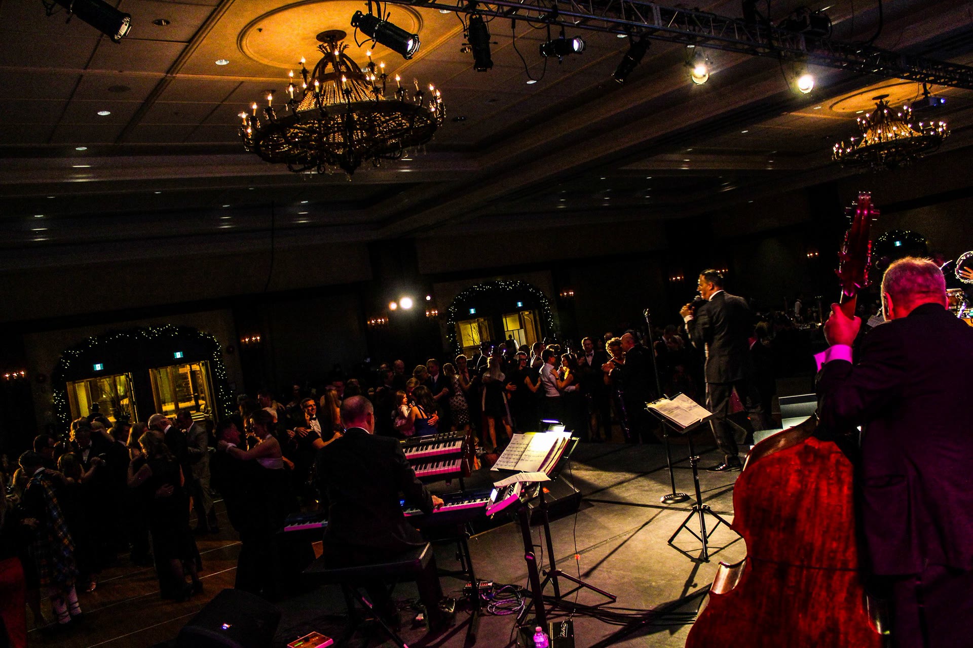 Barry Shaw performing to a packed gala dance floor under chandeliers